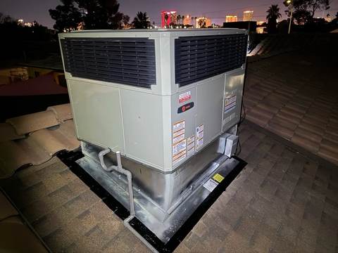 Rooftop package AC unit serviced at night with the Las Vegas Strip skyline visible in the background